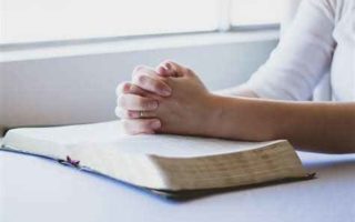 Praying hands on Bible